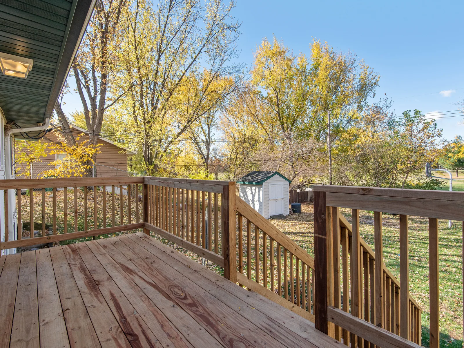 Wood deck with railings on the back of a house in autumn